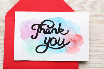 Wall Mural - Envelope and card with phrase Thank You on light wooden table, closeup. Top view