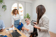 © Renata Hamuda - a smiling businesswoman in a wheelchair with a disability chatting with coworkers in office