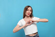 Beautiful young woman blowing kiss and making heart with hands on light blue background
