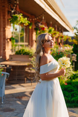 Wall Mural - beautiful blonde bride with a bouquet of callas on the path in the garden.