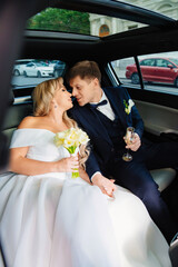 Wall Mural - the bride and groom in the back seat of the car. happy newlyweds. 