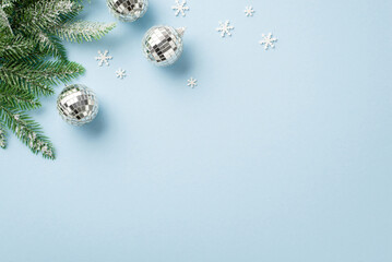 Wall Mural - Christmas tree decorations concept. Top view photo of disco balls snowflake shaped confetti and pine branches in snow on isolated pastel blue background with copyspace