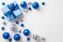 Christmas Concept. Top View Photo Of Blue White Silver Baubles Disco Balls And Big Giftbox With Ribbon Bow On Isolated White Background With Copyspace
