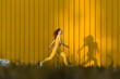 © VISTA by Westend61 - Woman running in front of yellow wall