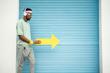 Man Wearing Headphones Walking With Yellow Arrow Sign By Shutter