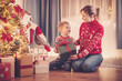 © candy1812 - Mother and son indoors sitting on the floor and giving present box each other in Christmas eve.