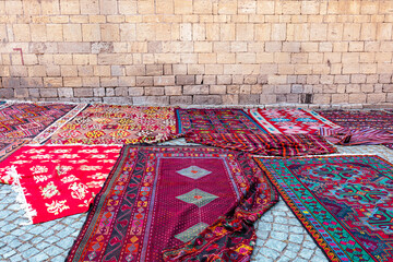 Wall Mural - A street market with many colorful carpets lying on a cobbled street in the old town of Baku, Republic of Azerbaijan. 