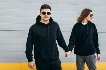 Wall Mural - Young adult men and woman in glasses and black hoodies 