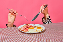 Female Hands With Fork And Knife Eating English Breakfast With Fried Eggs And Bacon