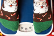 A woman in Christmas socks stands on the scales, weighs herself after gluttony during the holidays