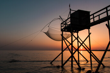  cabanes de pêche sur pilotis en Loire Atlantique appelées pêcheries face à l'océan et au soleil couchant