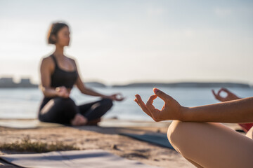 Wall Mural - Closeup of young sporty woman practicing yoga lesson with instructor, sitting in lotus pose