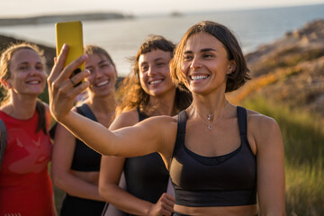 Wall Mural - Cheerful woman taking self portrait with positive girls around the nature