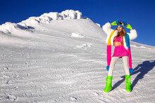 Winter Fashion. Beautiful Sexy Female Model Is Wearing Colorful Winter Outfit, Beanie, Scarf And Winter Boots. Attractive Young Woman In Wintertime Outdoor. Mountains, White Snow In Magic Winter Day
