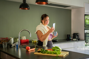 European woman messaging at the smartphone while enjoying coffee at home during the morning