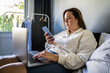 Focused european lady checking email at the smartphone while sitting at the bed