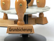 © M. Schuppich - Holzstempel mit dem Aufdruck 'Grundsicherung'