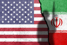 United States Of America And Iran Flags Painted On The Concrete Wall With Soldier Shadow. USA And Iran Conflict