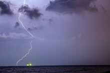 Lightning Struck On The Horizon Next To A Luminous Ship At Night