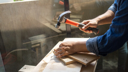 A man carves a tree. The carpenter works with a hammer in office.