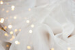 White tulle fabric background with bokeh overlay. Glitter chiffon texture, wedding concept.
