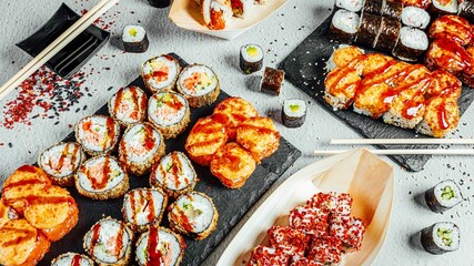 Wall Mural - High-angle shot of a set of delicious fresh sushi rolls served on a black board