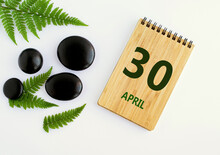 April 30. 30th Day Of The Month, Calendar Date. Notepad, Black Stones, Green Leaves. Spring Month, The Concept Of The Day Of Year