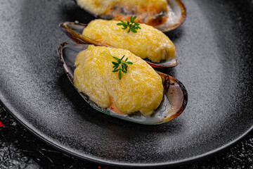 Canvas Print - Asian cuisine. Oysters baked with cheese in a black plate on a black background.