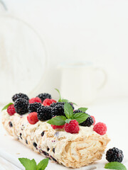 Wall Mural - Baked meringue roll with cream and fresh fruits on a white wooden board, delicious dessert