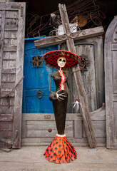 Wall Mural - Skeleton statue with sombrero with wooden doors in the background