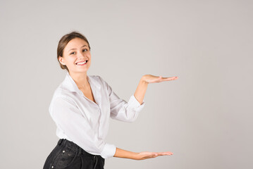 Wall Mural - A businesswoman shows a product with a copy space for advertising on a gray background.