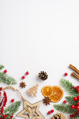 Wall Mural - Christmas decorations concept. Top view vertical photo of wooden star ornament dried orange slices cinnamon sticks mistletoe berries pine cone fir branches on isolated white background with copyspace