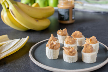 Wall Mural - Healthy banana snack with peanut butter on kitchen table background