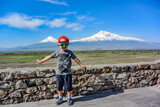 Fototapeta Tęcza - Little boy on the background of a beautiful view of mount Ararat in the afternoon. May 6, 2019. Armenia.