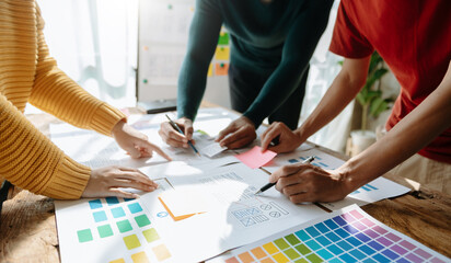 UX developer and ui designer brainstorming about mobile app interface wireframe design with customer breif and color code at office..