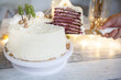 Winter cake with white cream decorated with gold hazelnuts, confectionery sprinkles and green New Year trees