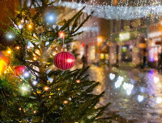  Christmas red ball  festive holiday street decoration green tree branch people walk with umbrella evening blurred light medieval city Talluinn old town