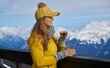 © ZoomTeam - Woman drinking warm tea in the rustic wooden terrace on mountain, alpine view, snow on hills.