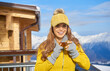 © ZoomTeam - Woman drinking warm tea in the rustic wooden terrace on mountain, alpine view, snow on hills.