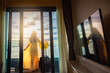 © shine - Hotel vacation happy Asian woman tourist in yellow summer dress with her luggage and enjoying ocean view from balcony hotel room and Beautiful sunset above sea or ocean, reflection of sun in the water