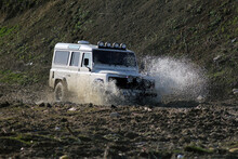 A 4WD Land Rover Defender Passing Through And Splashing Water A Puddle 