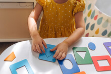 A Little Girl Playing With Wooden Shape Sorter Toy On The Table In Playroom. Educational Boards For Color And Shapes Sorting For Toddler. Learning Through Play. Developing Montessori Activities.
