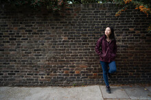 Asian Woman Leaning On Brick Wall