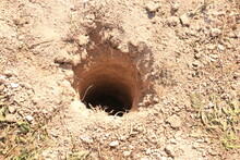 A Deep, Round Hole In The Ground For A Post When Building A Fence. Digging Holes In The Ground For Planting A Tree Seedling.