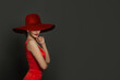 Beautiful woman in red wide broad brim hat against grey background