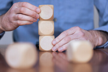 Wall Mural - Close up of a business person arranging large wooden blocks. Business strategy and solutions