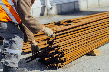 Slinger stacks thin metal pipes in stack on construction site. Close-up. Real workflow. Unloading of materials for construction. Production background for equipment supplier..