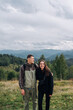 © bodnarphoto - Happy young tourist couple man and woman in the mountains during a hike standing with smiles on their faces and hugging.