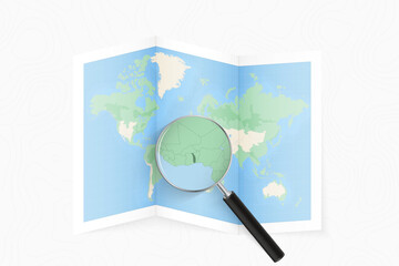 Wall Mural - Enlarge Togo with a magnifying glass on a folded map of the world.