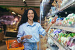 © Liubomir - Portrait of beautiful vegetarian woman in supermarket, Latin American woman chooses vegetables for dinner, smiling and looking at camera.